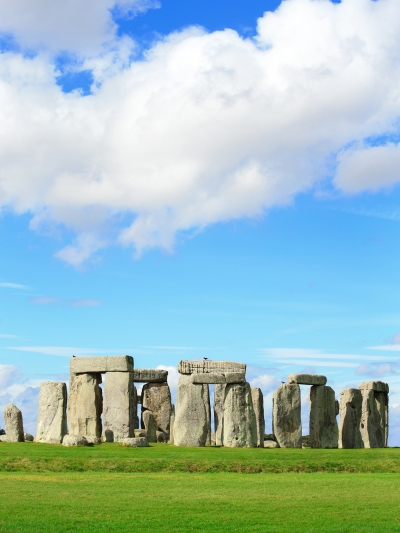 A photo of a stonehenge-like monument with a large stone pillar in the center and smaller stones arranged around it.