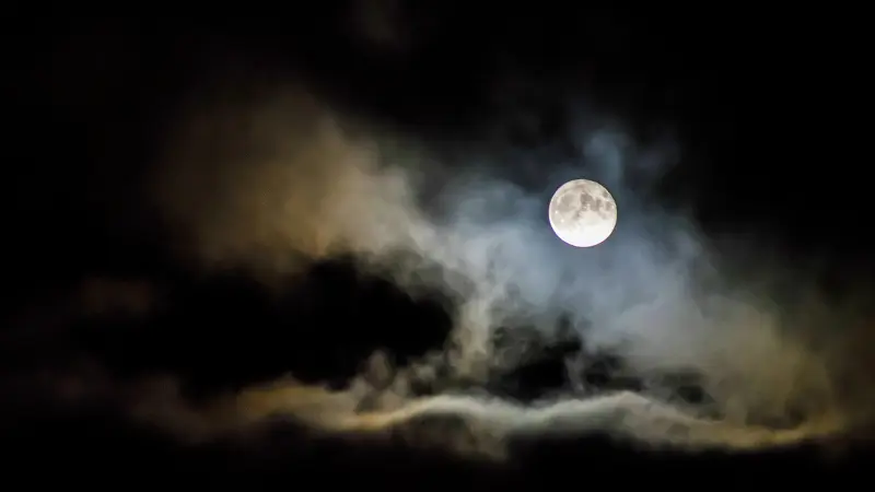 Moon in sky behind clouds